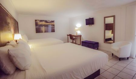 A hotel room with two beds , a chair , a desk and a television.