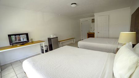 A hotel room with two beds and a flat screen tv