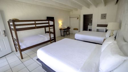 A hotel room with two beds and a bunk bed