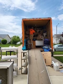 A man is loading a moving truck with boxes on a ramp.