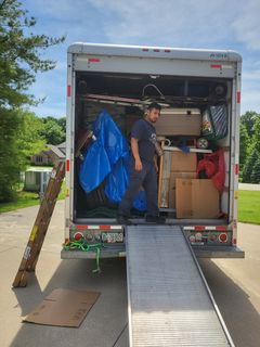 A man is standing in the back of a moving truck.