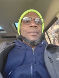 A man wearing a beanie and glasses is sitting in a car.