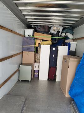 The inside of a moving truck filled with boxes and luggage.