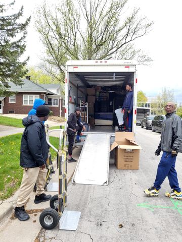 A group of men are standing in front of a moving truck.
