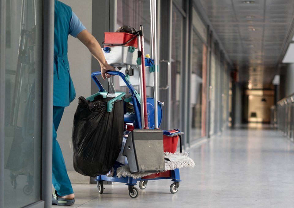 Cleaner Pulls A Trolley With Cleaning Equipment — Wichita, KS — Top Priority Concierge