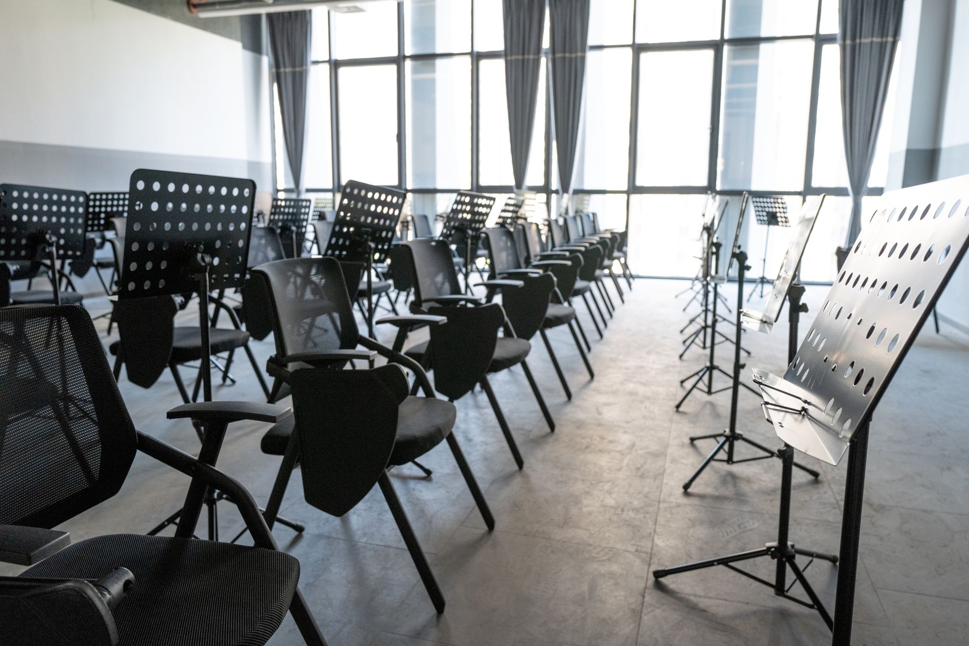 Music room with rows of chairs, music stands, and a large window.