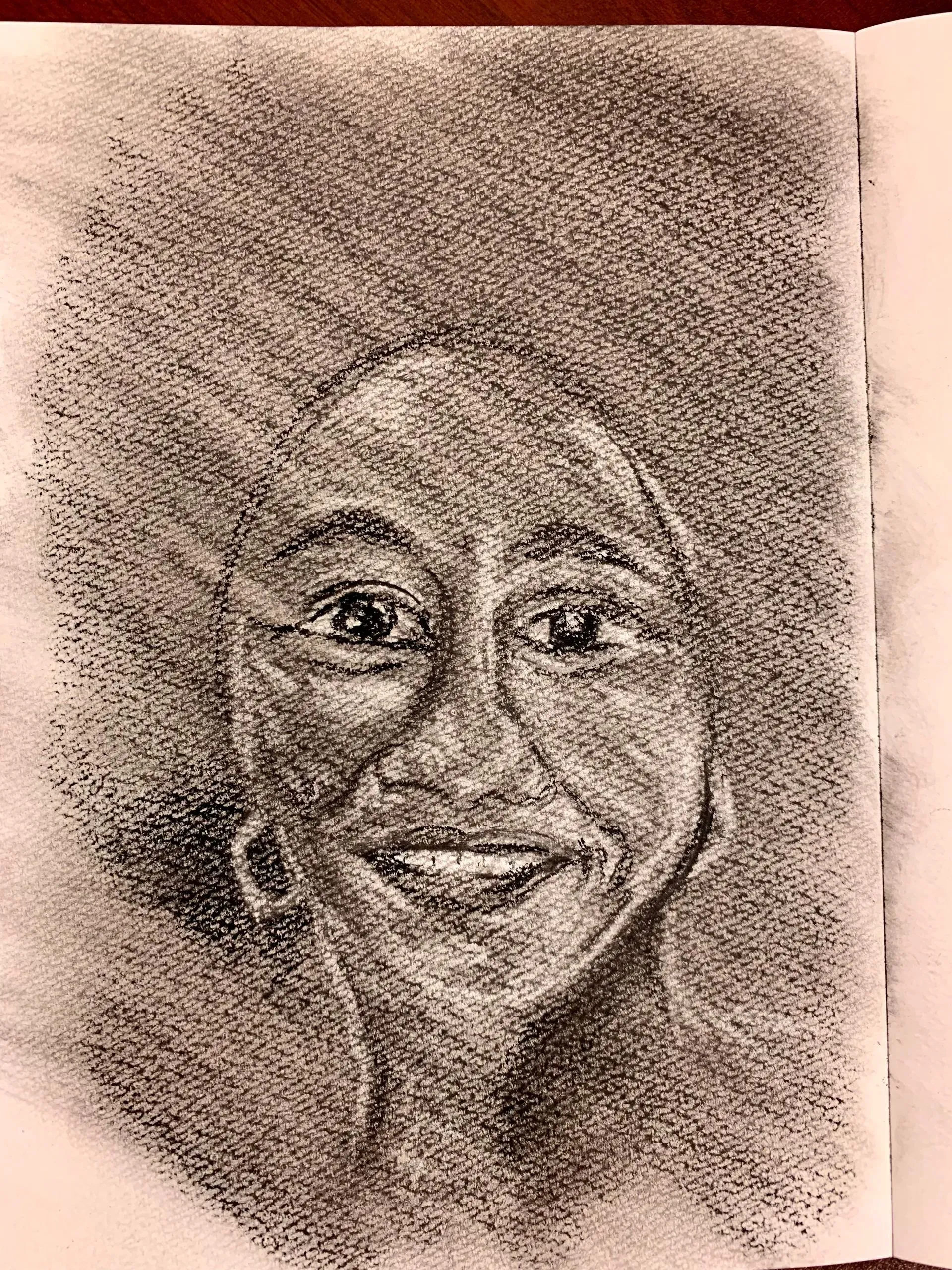 Smiling person with dark skin and large afro, drawn in charcoal on paper.