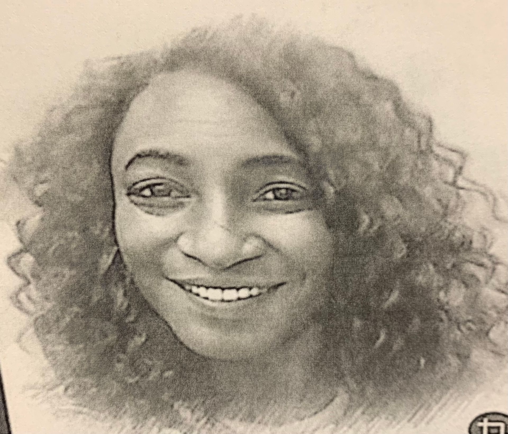 Smiling woman with curly hair, rendered in grayscale.