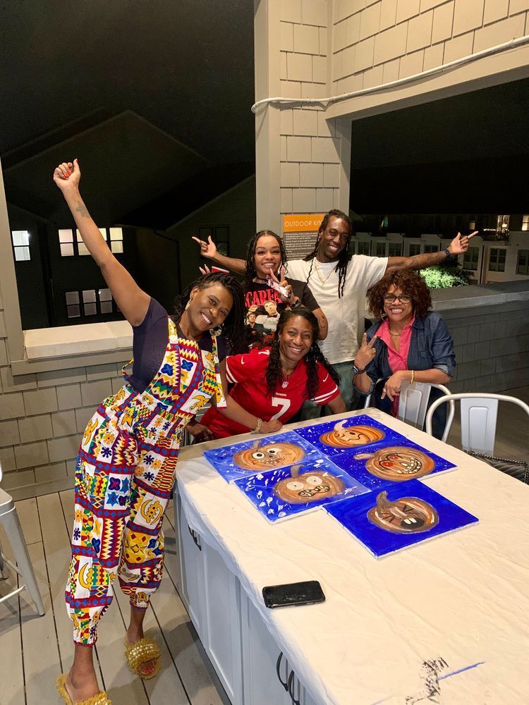 Group of five people celebrating at night; they are around a table with decorated pizza.