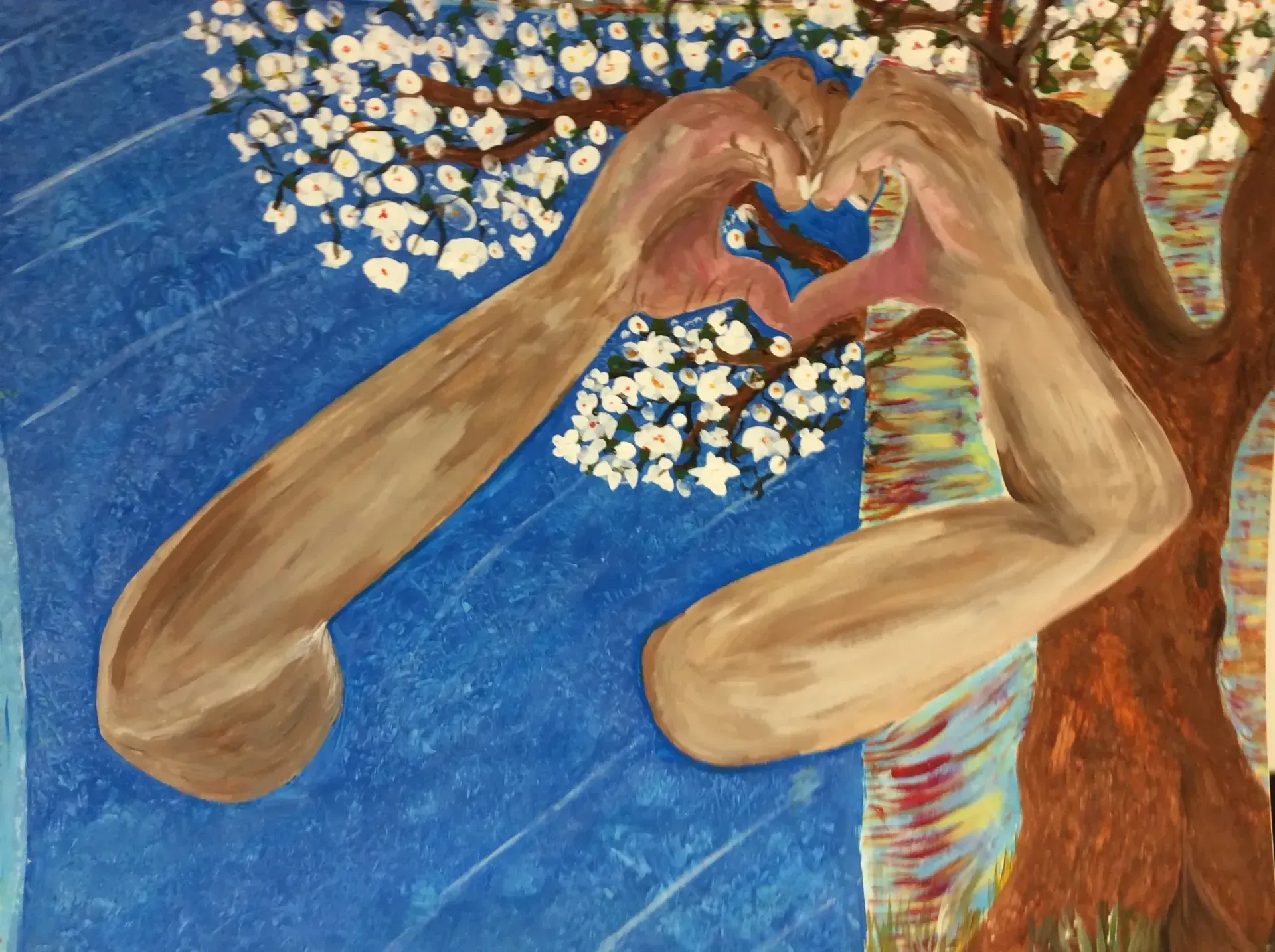Hands forming a heart against a blue background, a tree, and white blossoms.