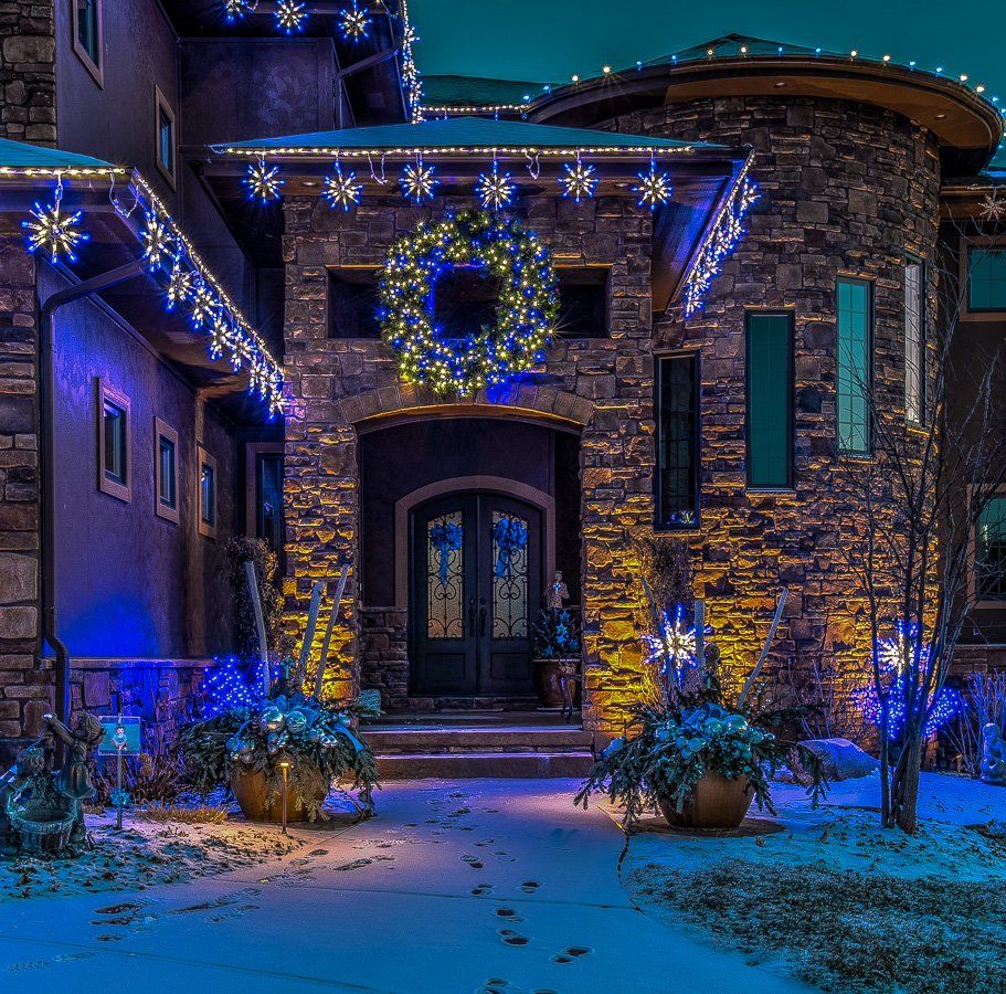 A large stone house decorated with christmas lights and a wreath