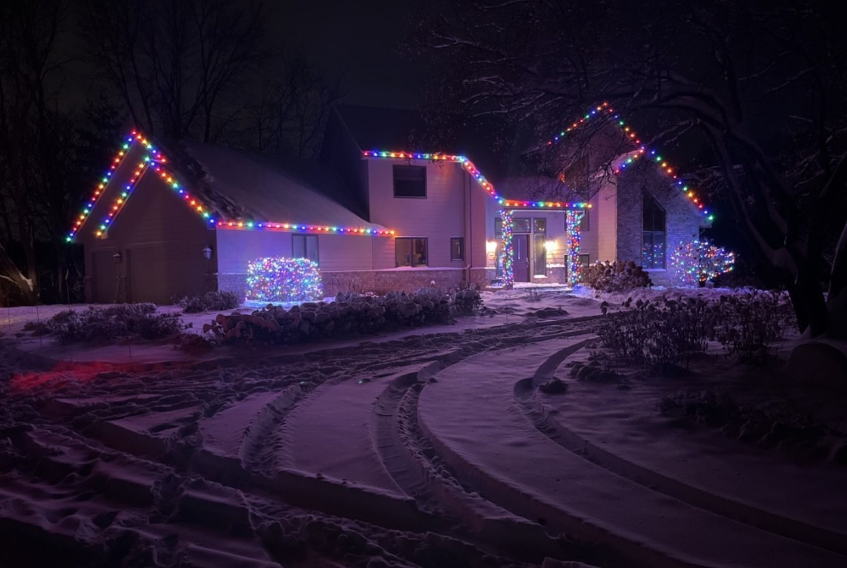 Holiday lights glowing through trees and rooftops in Victoria, MN’s Laketown neighborhood