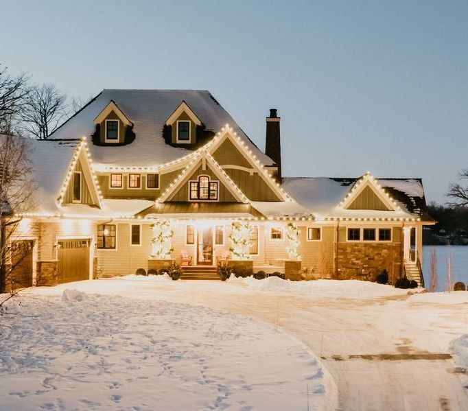 the house is decorated with christmas lights and is covered in snow .