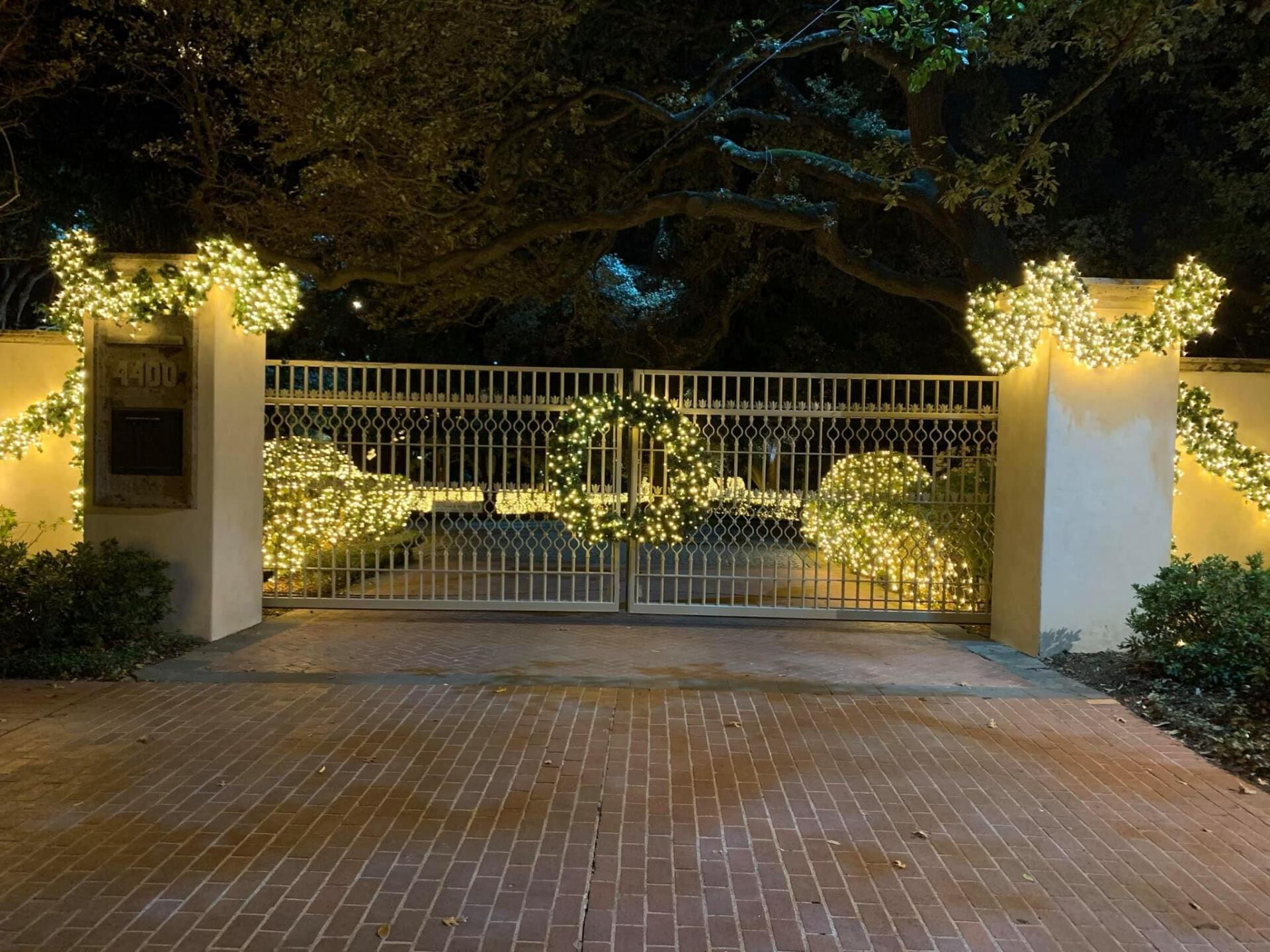A brick driveway with a gate decorated with christmas lights