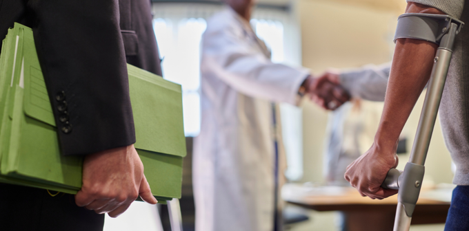 a man with crutches is shaking hands with a doctor .