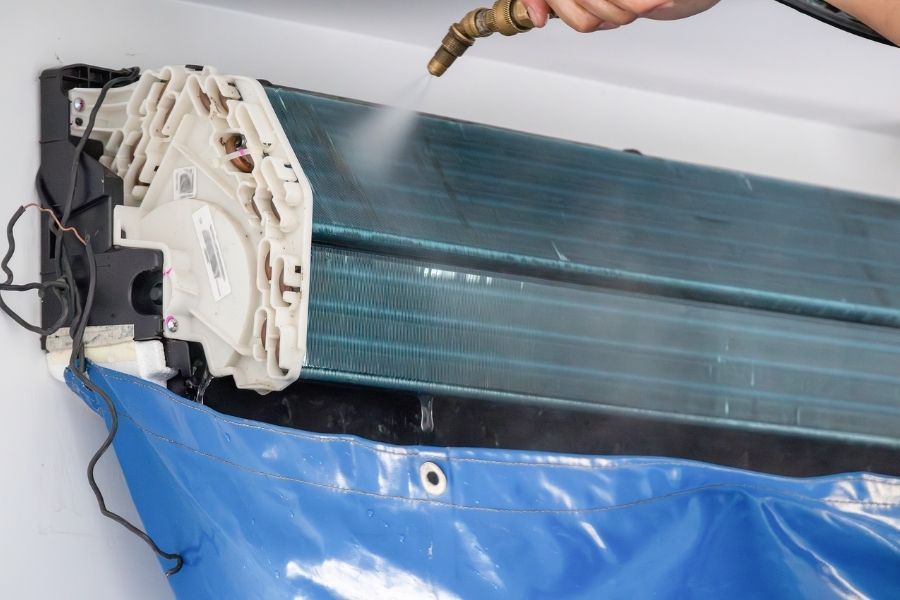 HVAC evaporator coil being pressure washed with a protective tarp beneath