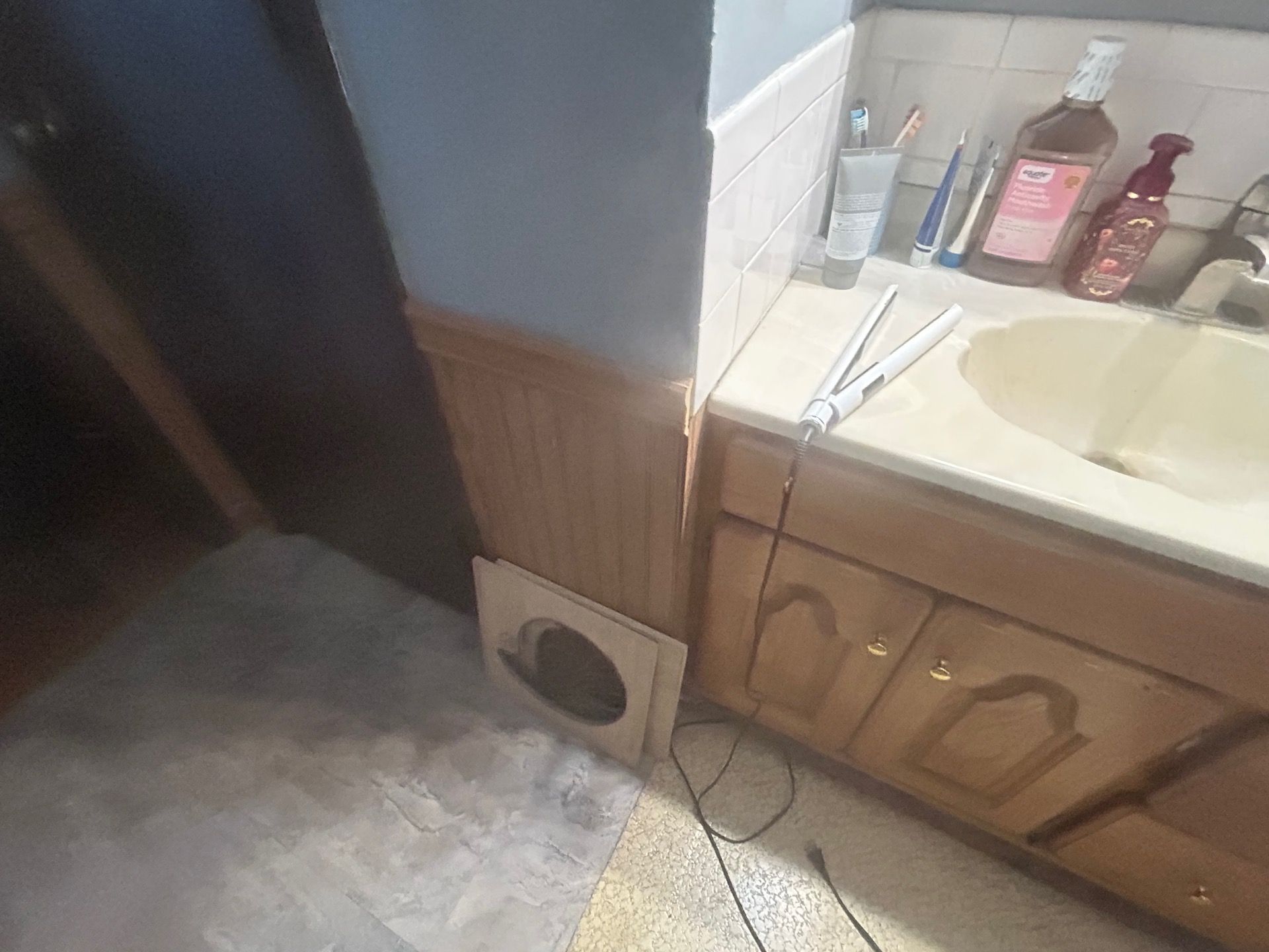 Vanity removed and subfloor exposed during bathroom water damage restoration