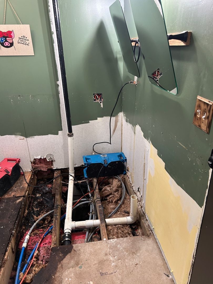 Exposed plumbing and subfloor during water damage mitigation in Hartville bathroom