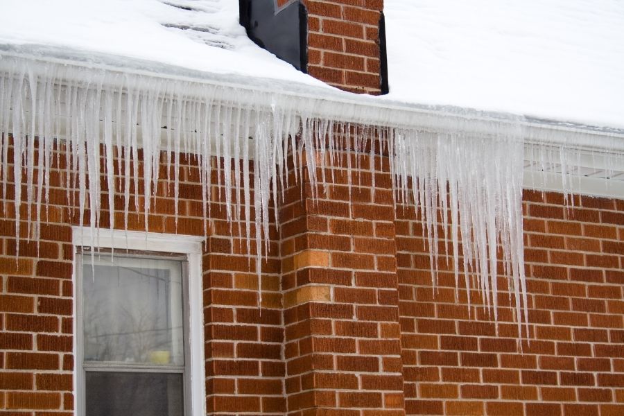Brick house with gutters covered in long icicles hanging down