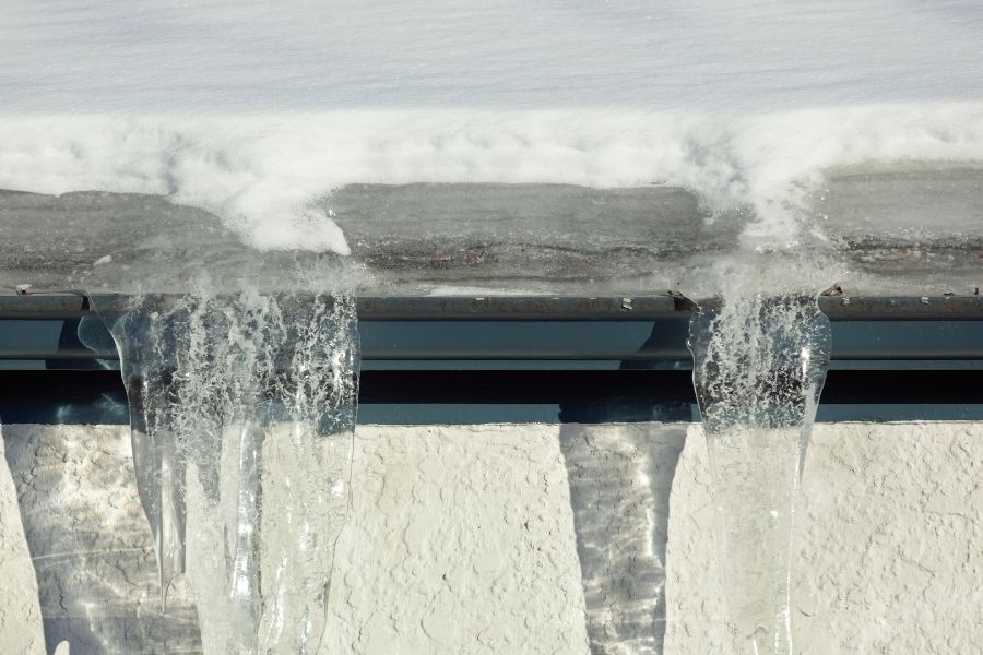 Close-up view of ice dam formation on gutters with icicles