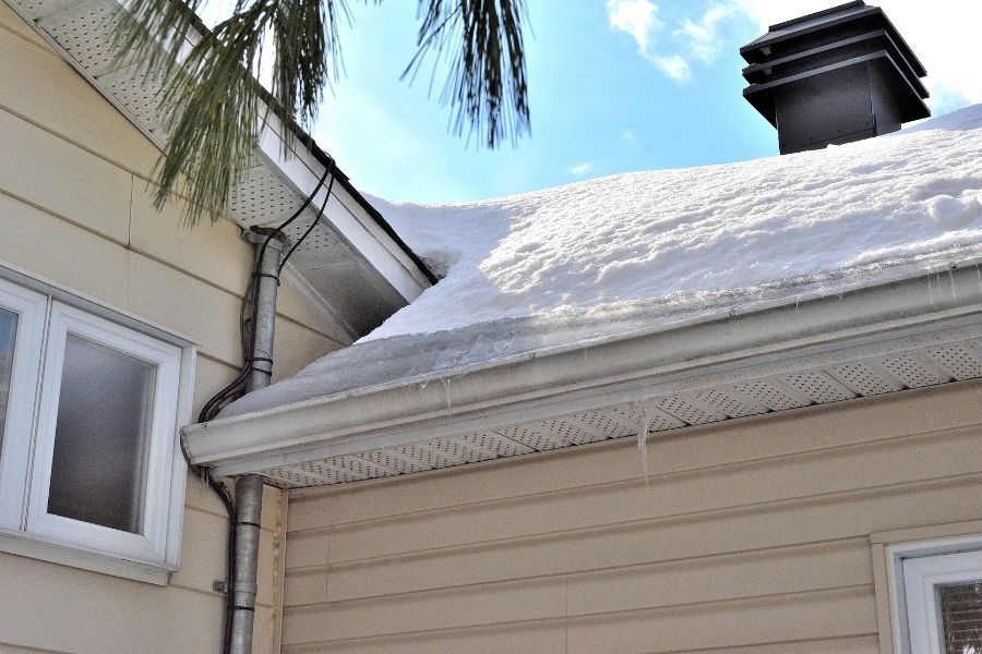 Snow-covered residential roof showing early signs of ice dam formation