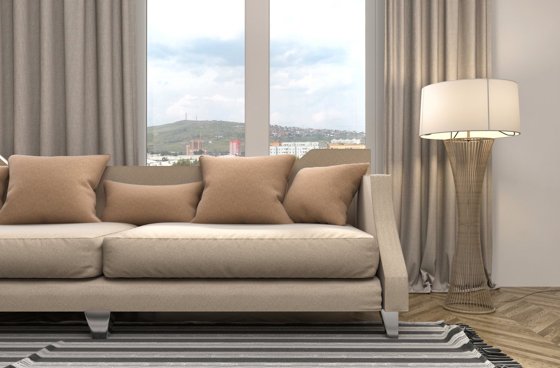 Neutral toned living room with drapes open behind comfy fabric couch with cushions, striped rug and freestanding lamp.