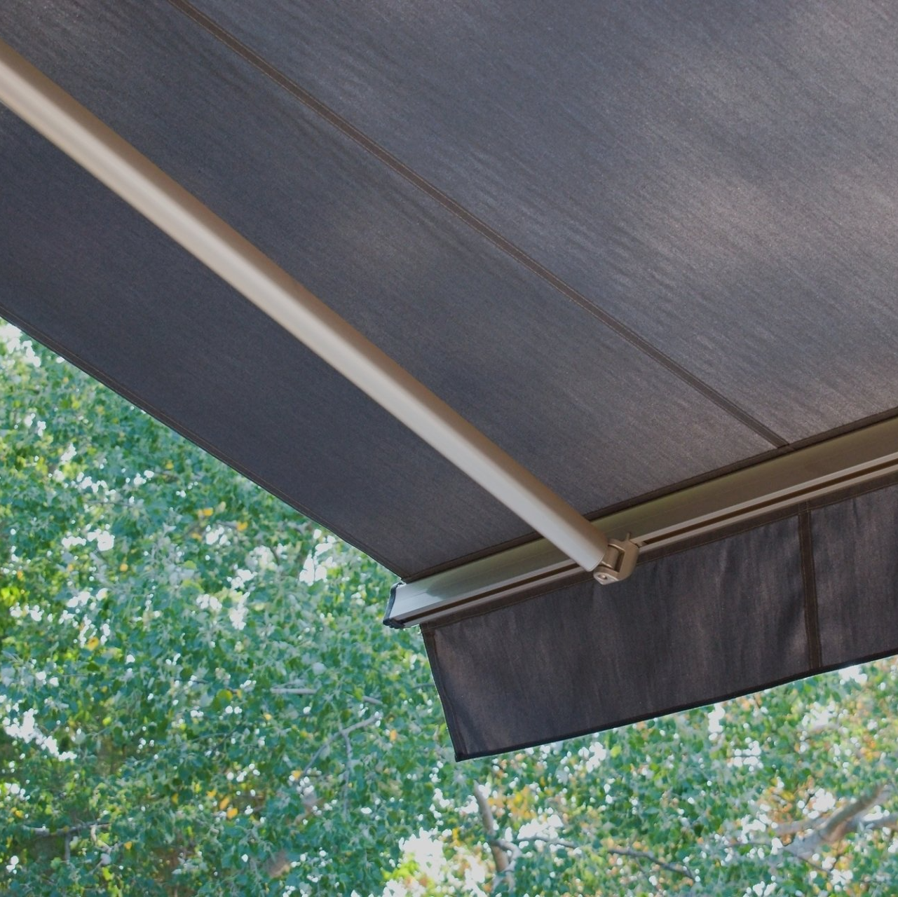 Close up of dark external awning, with green tree in background.