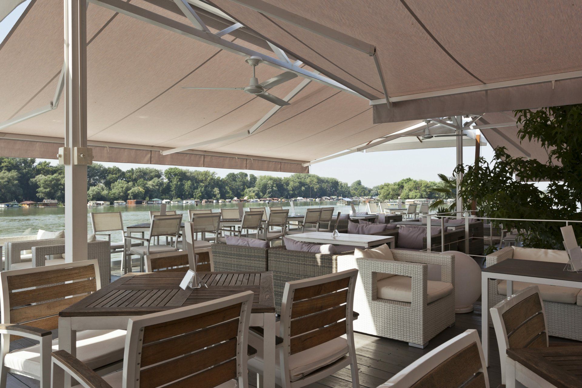 Outdoor awning extending out over outdoor commercial dining area with timber tables and chairs.