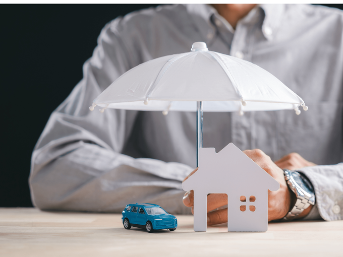 Mini house model covered by a white umbrella held by a person, symbolizing protection from a home and auto insurance broker service in San Tan Valley, AZ