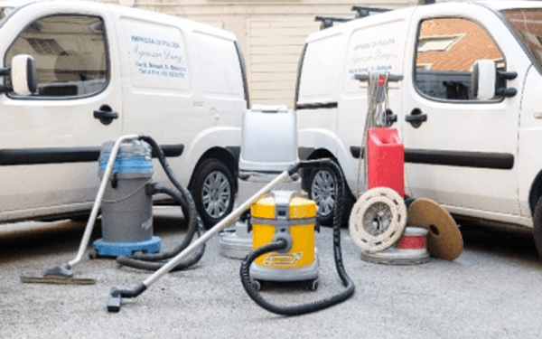 Due furgoni bianchi sono parcheggiati uno accanto all'altro con degli aspirapolvere davanti