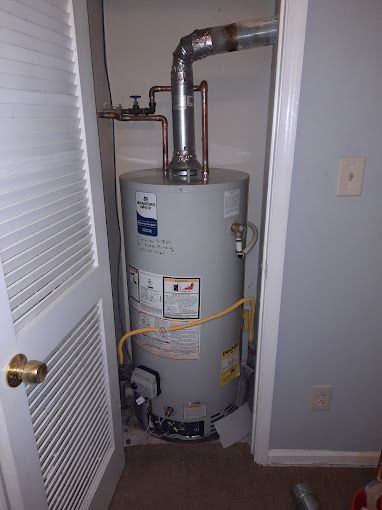 A water heater is sitting in a closet next to a door.