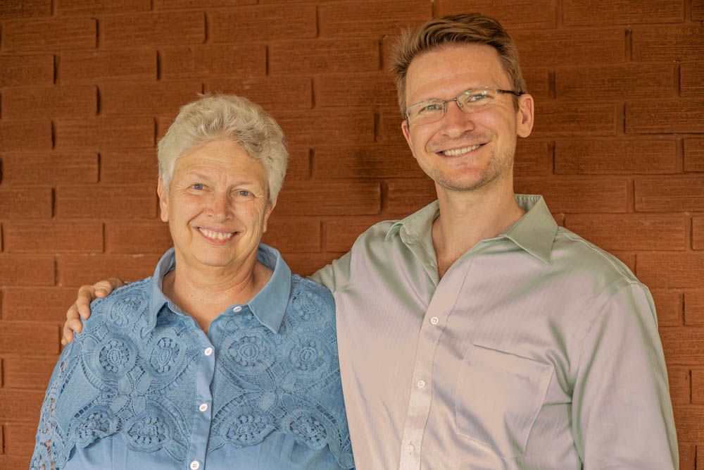 A man and a woman are posing for a picture in front of a brick wall.