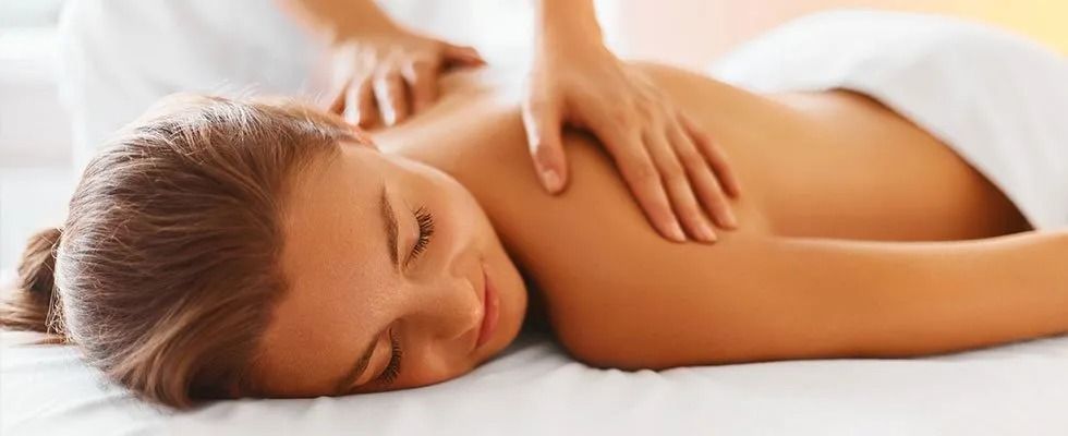 A woman is laying on a bed getting a massage.