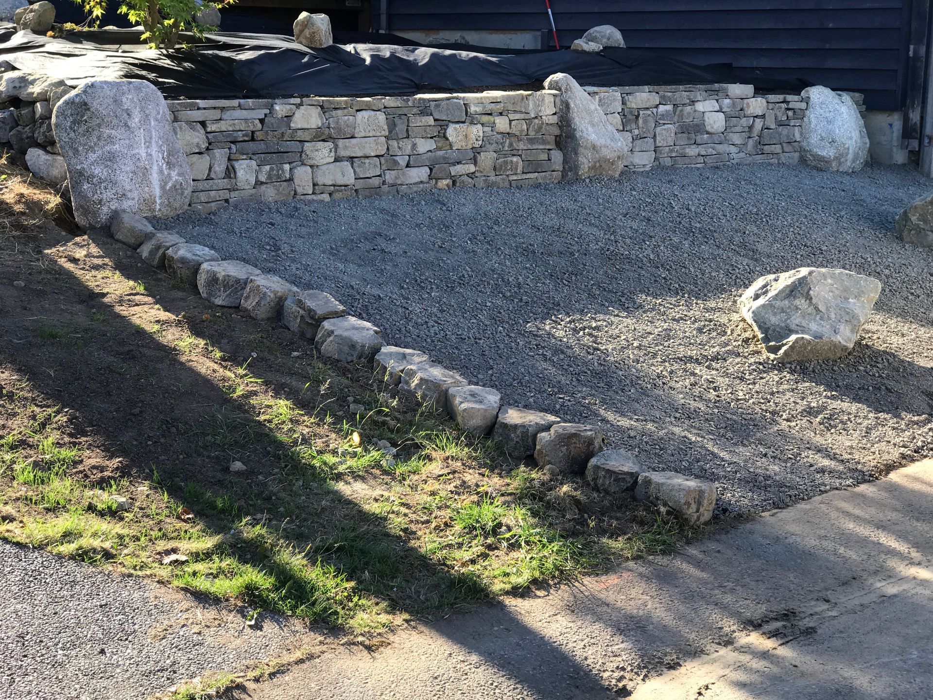 Stone retaining wall and gravel garden bed with large boulders; work by West Coast Landscape & Hardscape. 