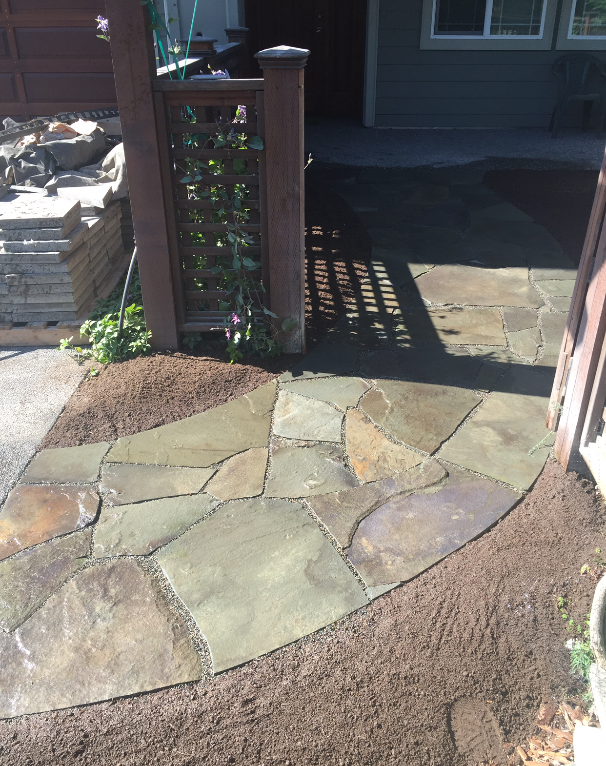 Stone pathway leading to a shaded doorway, surrounded by brown mulch; work by West Coast Landscape & Hardscape. 
