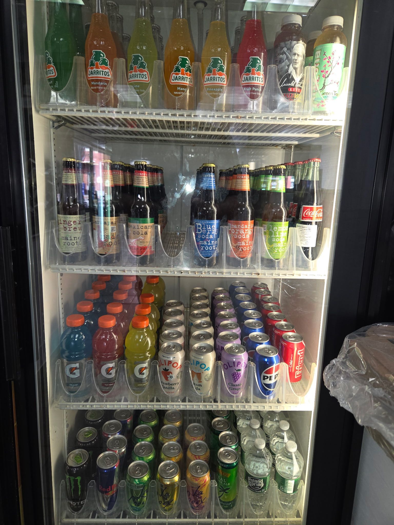 A refrigerated display case stocked with various bottled and canned beverages.
