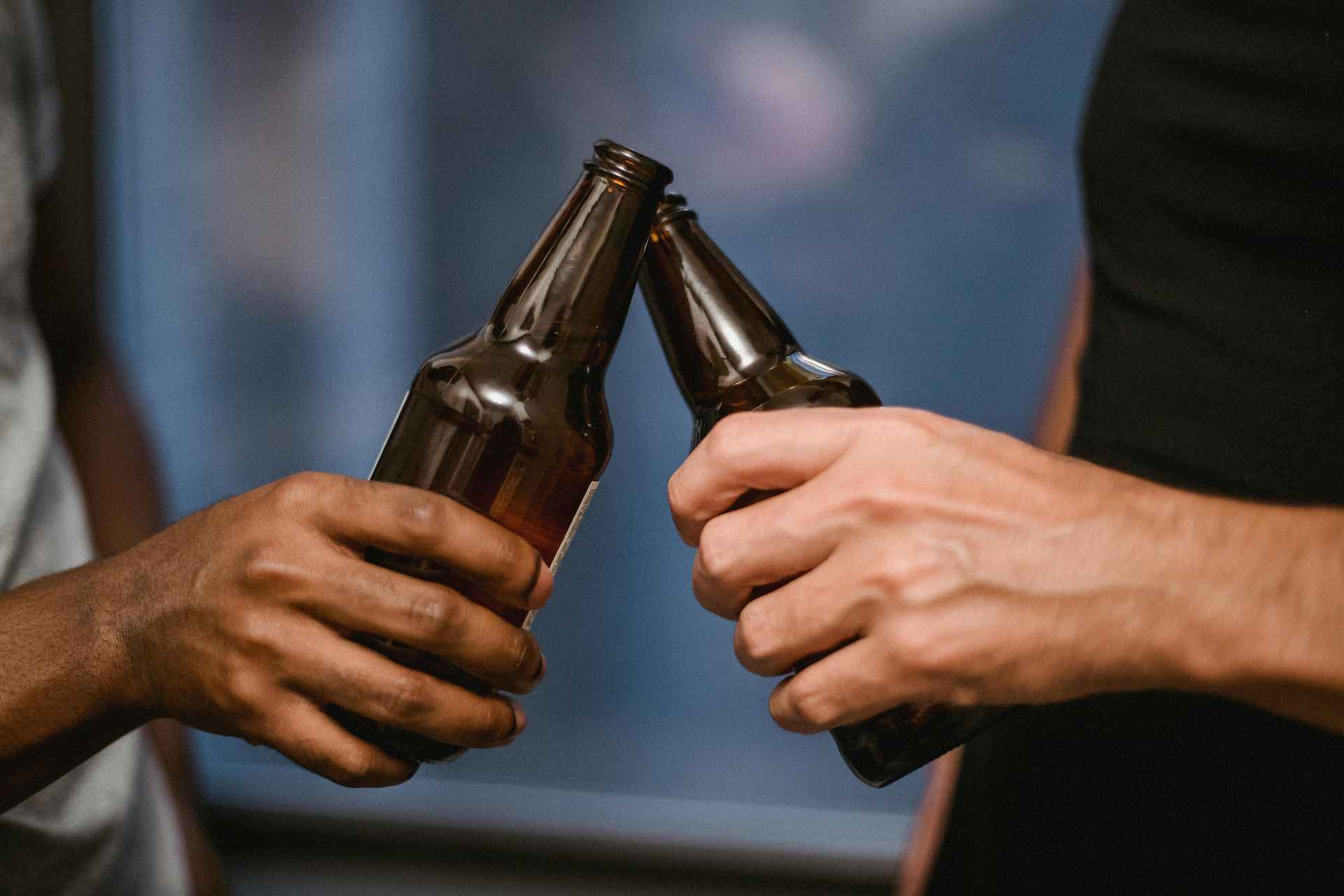 Two people toasting beer bottles.