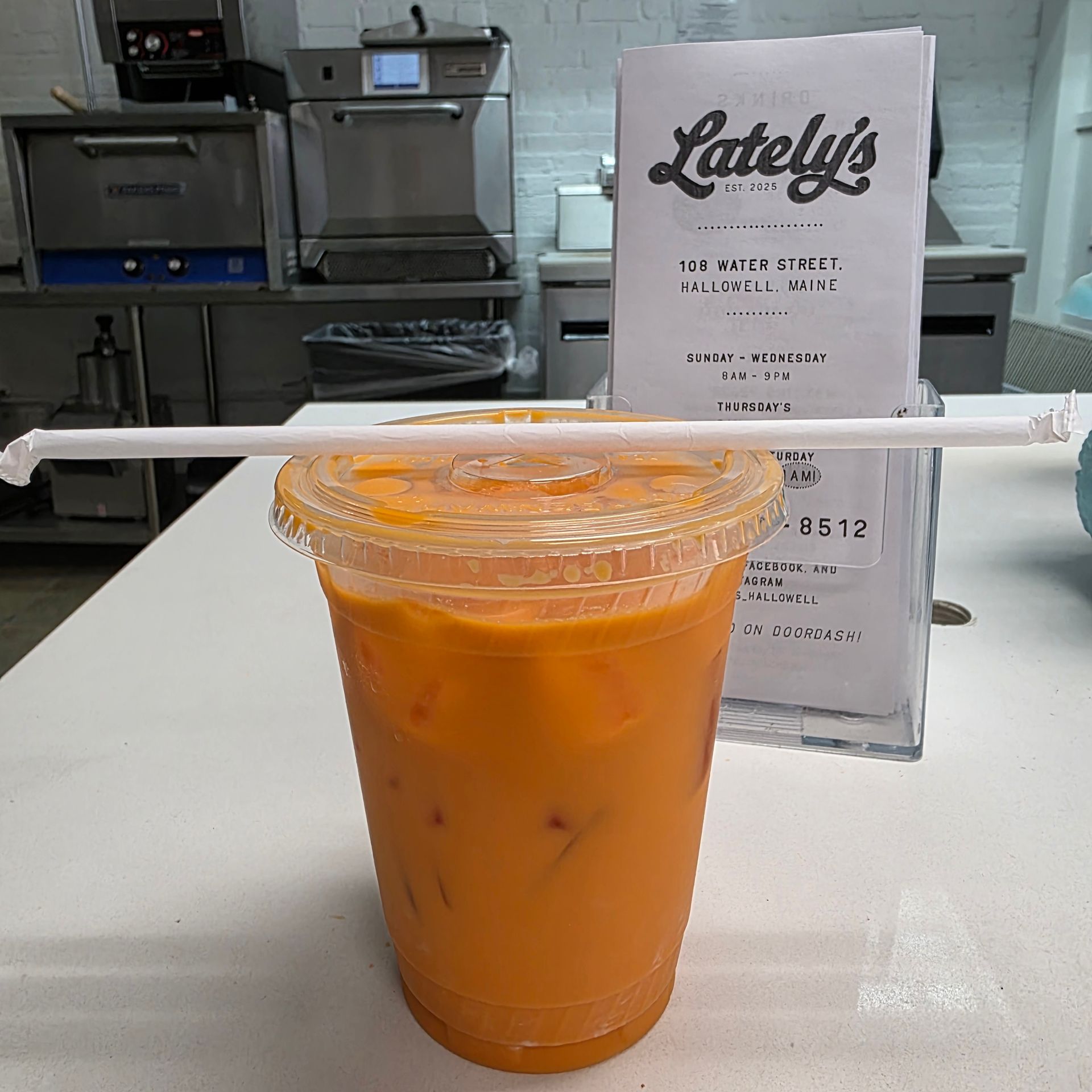 Person holding a clear plastic cup with a milky drink and dark pieces; orange berries in background.