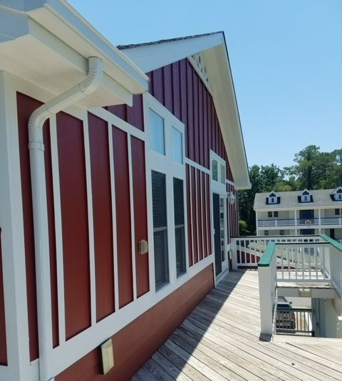 A man is installing siding on the side of a house.