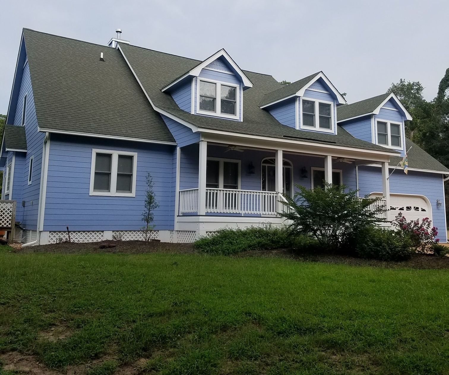 A man is standing on a ladder painting a house.