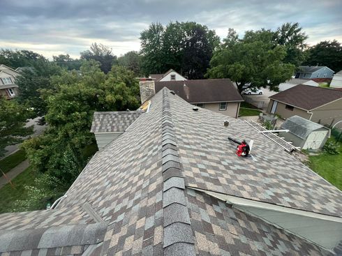 An aerial view of a roof of a house with trees in the background.