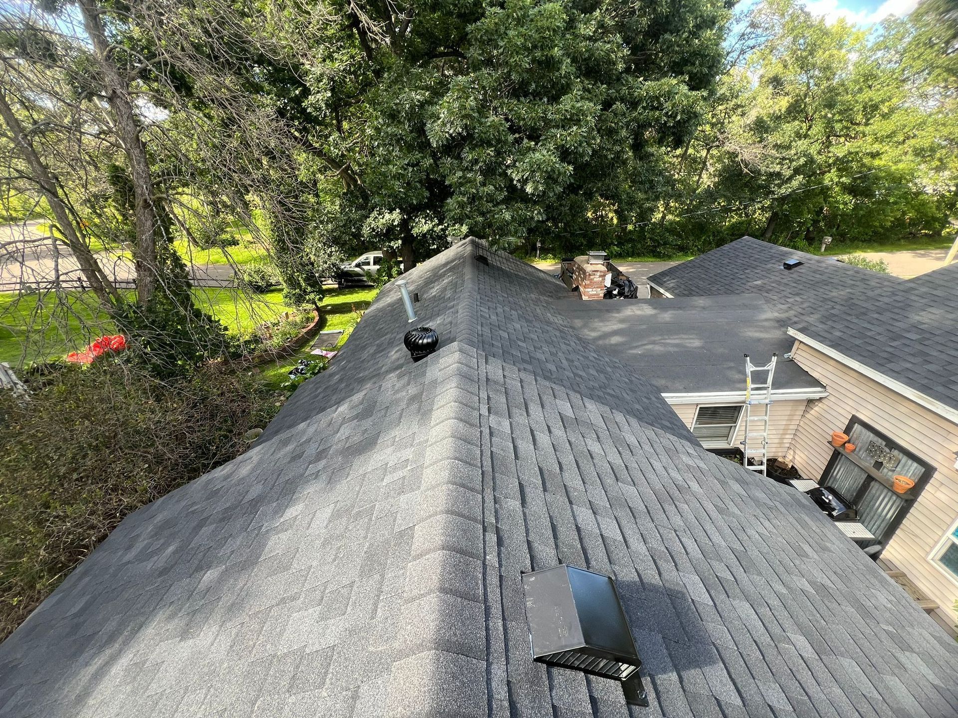 An aerial view of a roof of a house with trees in the background.