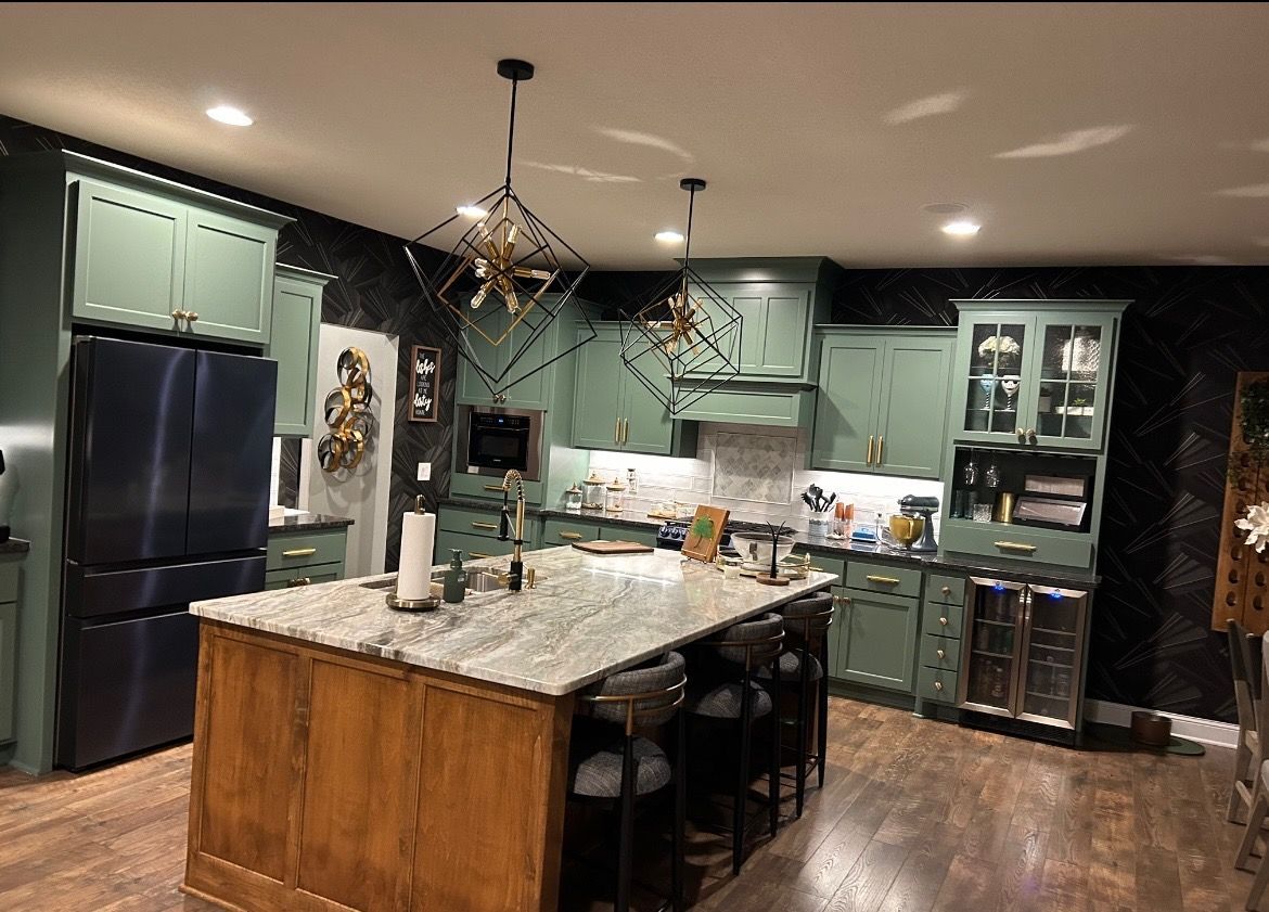 A kitchen with green cabinets and a large island in the middle.