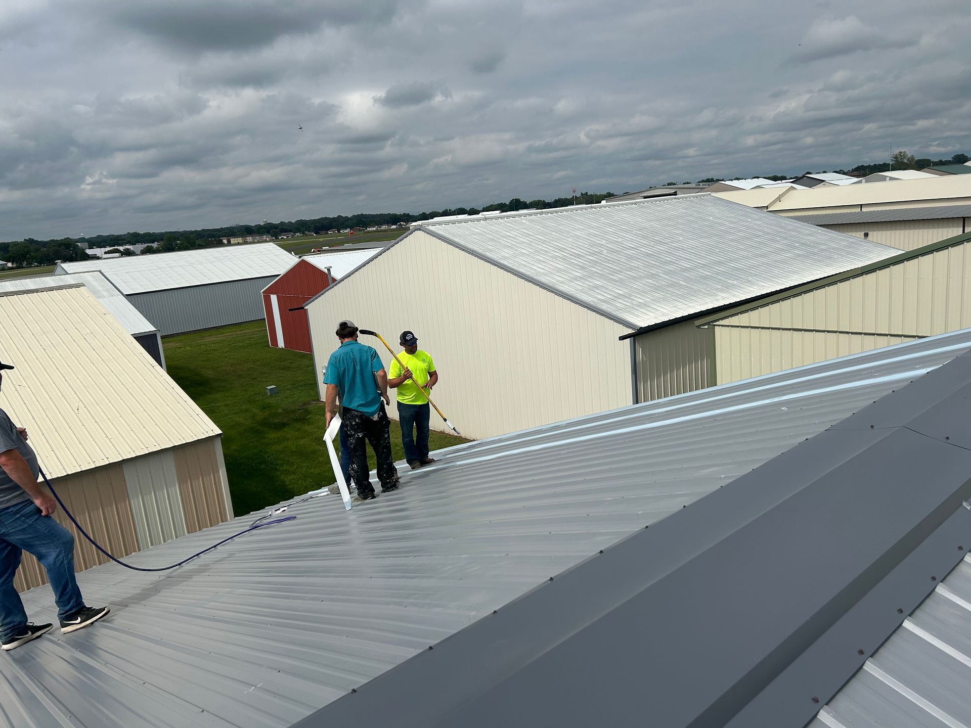 A group of men are standing on top of a metal roof.