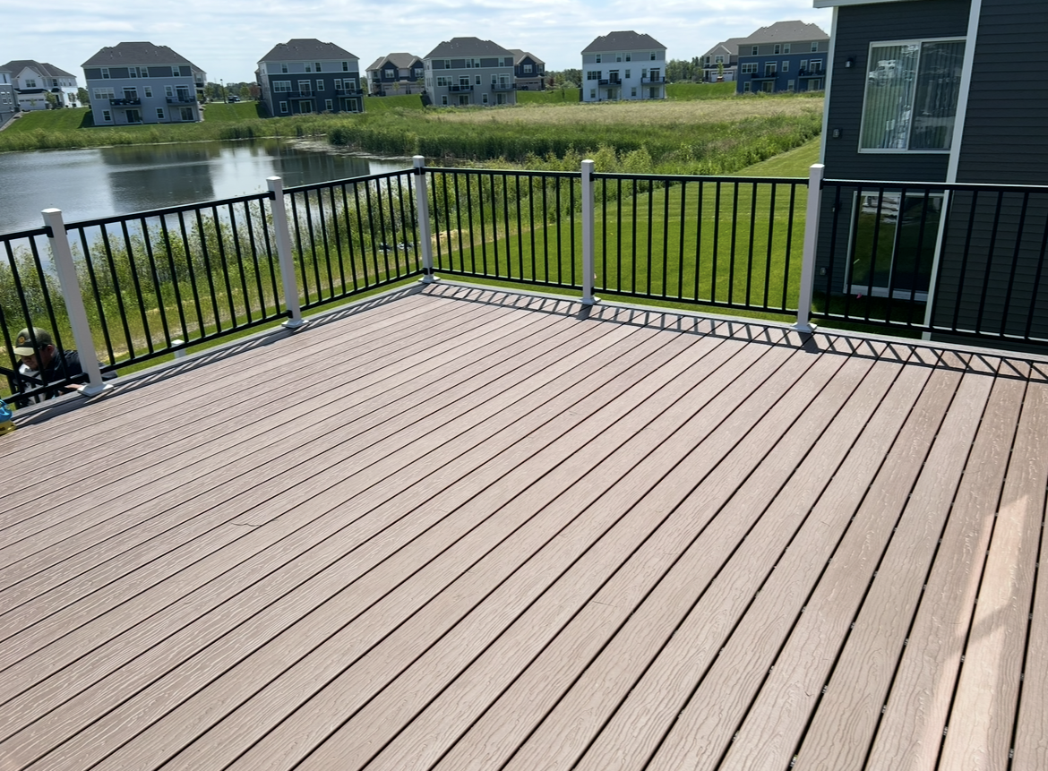 A large deck with a fence and a view of a lake.