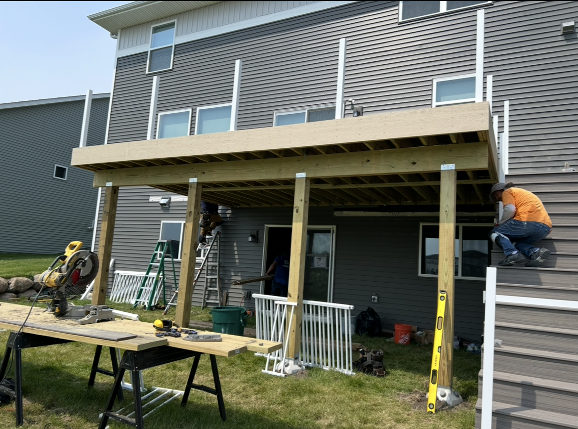 A man is working on a deck in front of a house.
