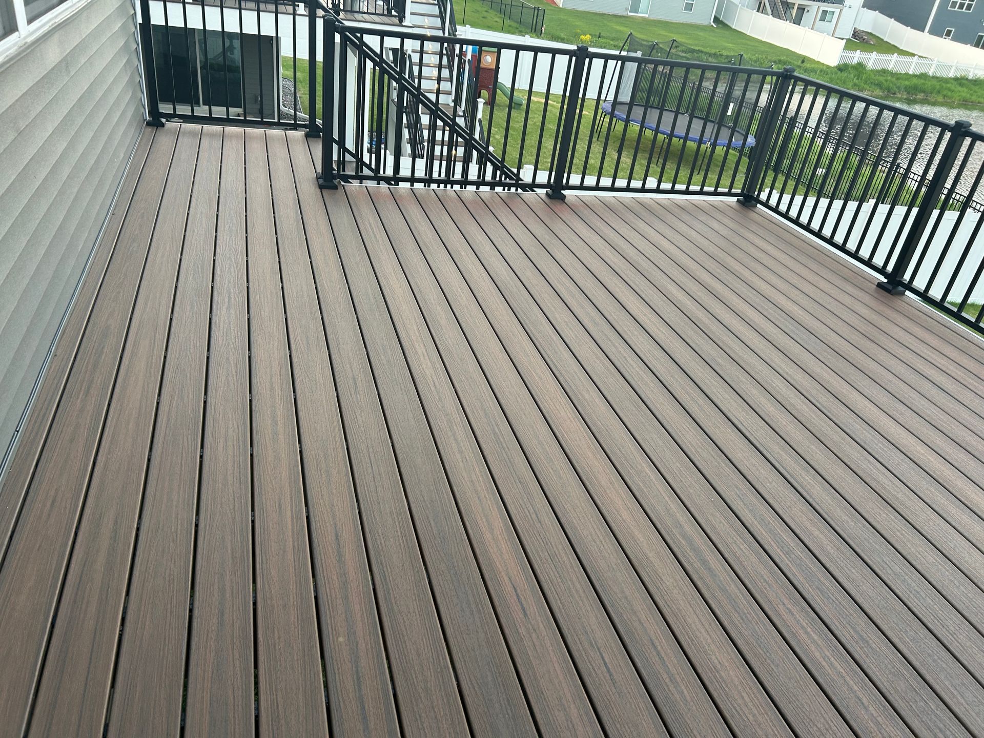 A wooden deck with a metal railing and stairs leading up to it.