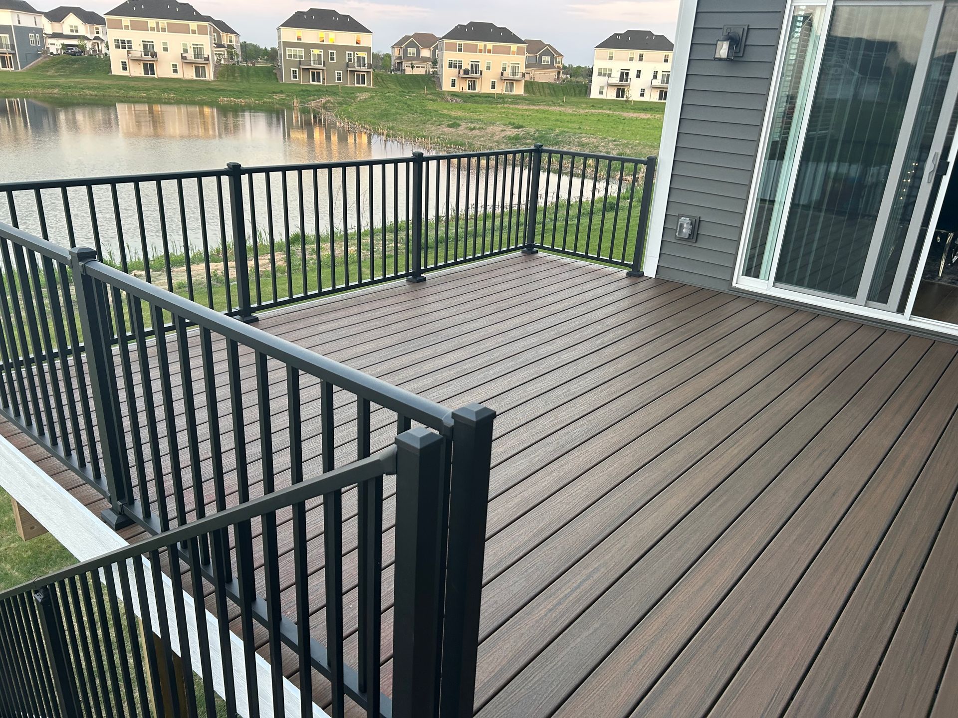 A large deck with a black railing and a view of a lake.