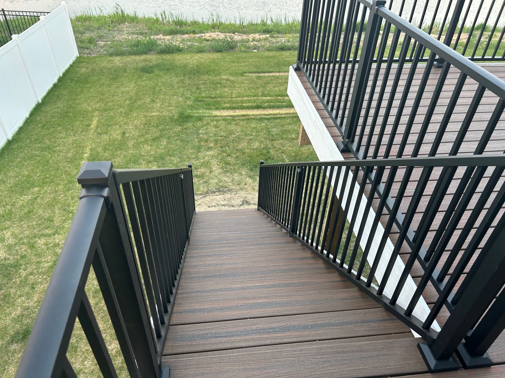 A set of stairs leading up to a deck with a black railing.