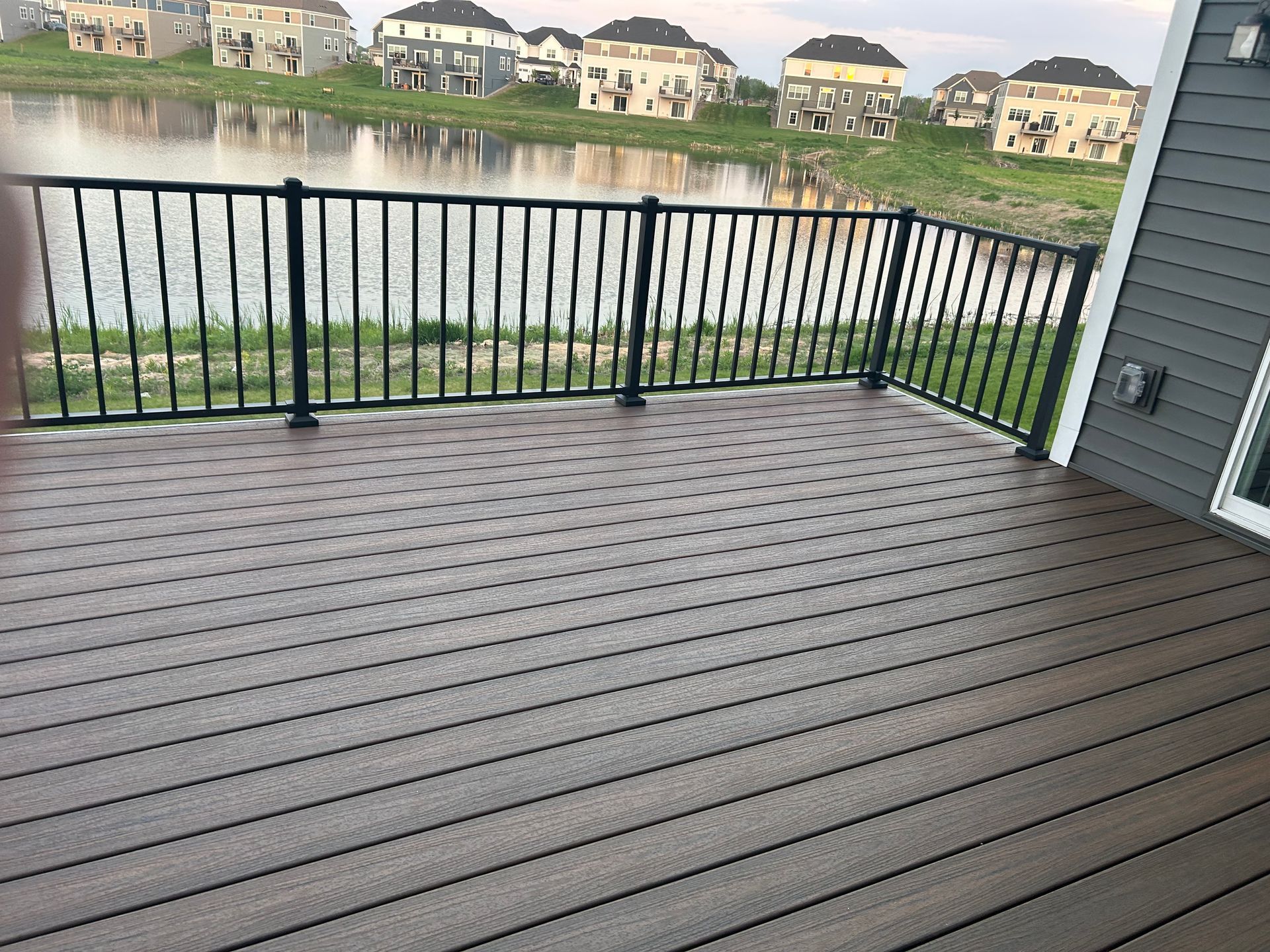 A wooden deck with a metal railing overlooking a lake.